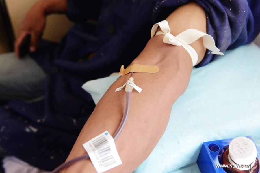 A migrant worker donates blood in a mobile blood collection vehicle in Qingdao, east China's Shandong Province, June 14, 2013, on the occasion of the World Blood Donor Day.